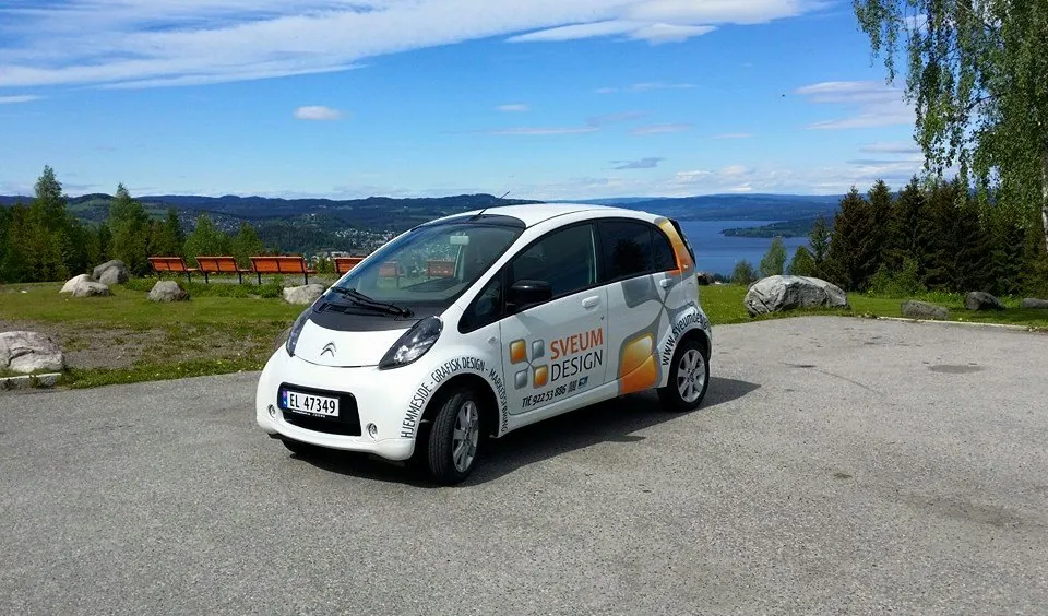 Hvit Citroën med tidligere Sveum Design-profil, parkert på det samme utsiktspunktet over Mjøsa i 2016