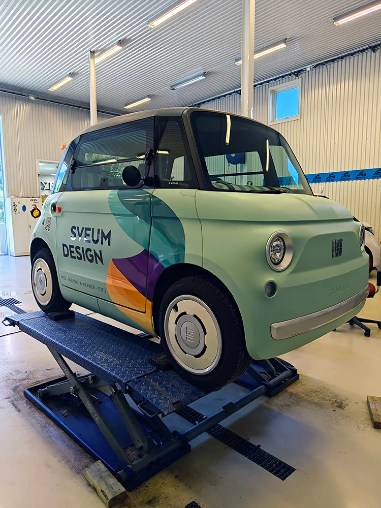 Fiat Topolino ferdig foliert med Sveum Design-profil, på løftebukk i et verksted