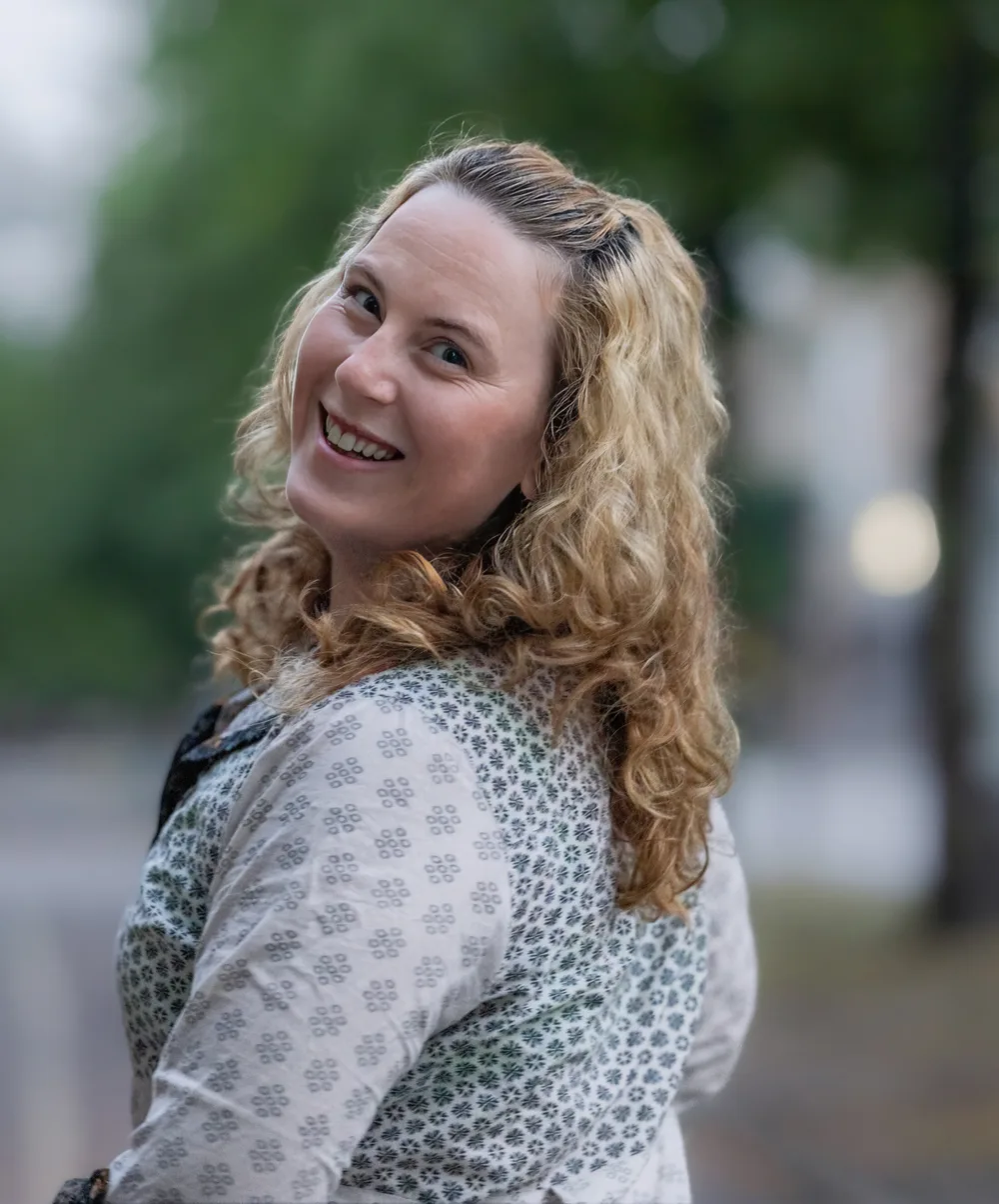 Kristine Sveum smiler over skulderen, fotografert utendørs