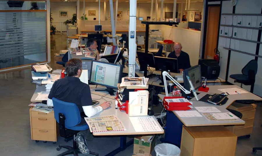 Kristine på desken i Oppland Arbeiderblad, med TV-Innlandet i bakgrunnen